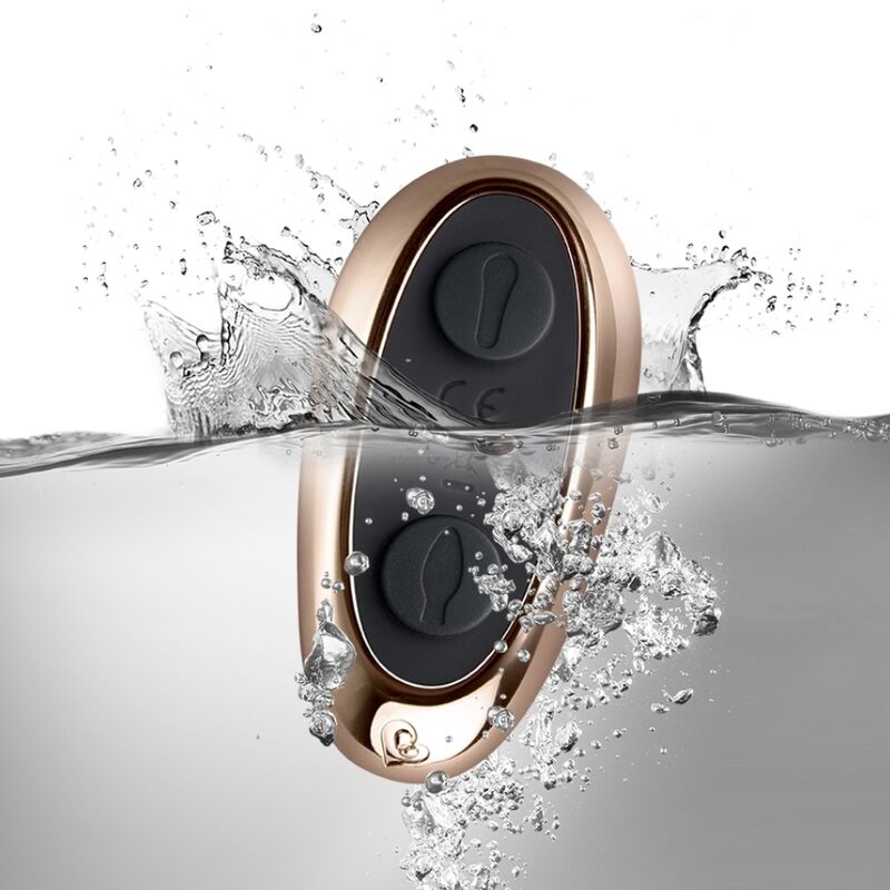 Rocks-Off Cocktail Plug negro y dorado con mando a distancia, salpicando en el agua.