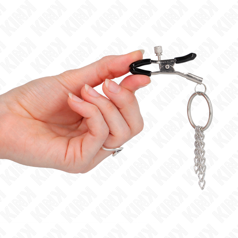 Detalle de las Kink Nipple Grip: pinza negra con aro y cadena plateada en la mano.