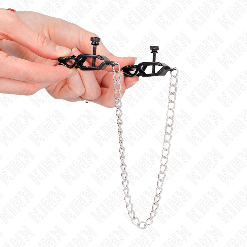 Detalle de KINK Nipple Grip: pinzas negras con cadena plateada sujetas en la mano.