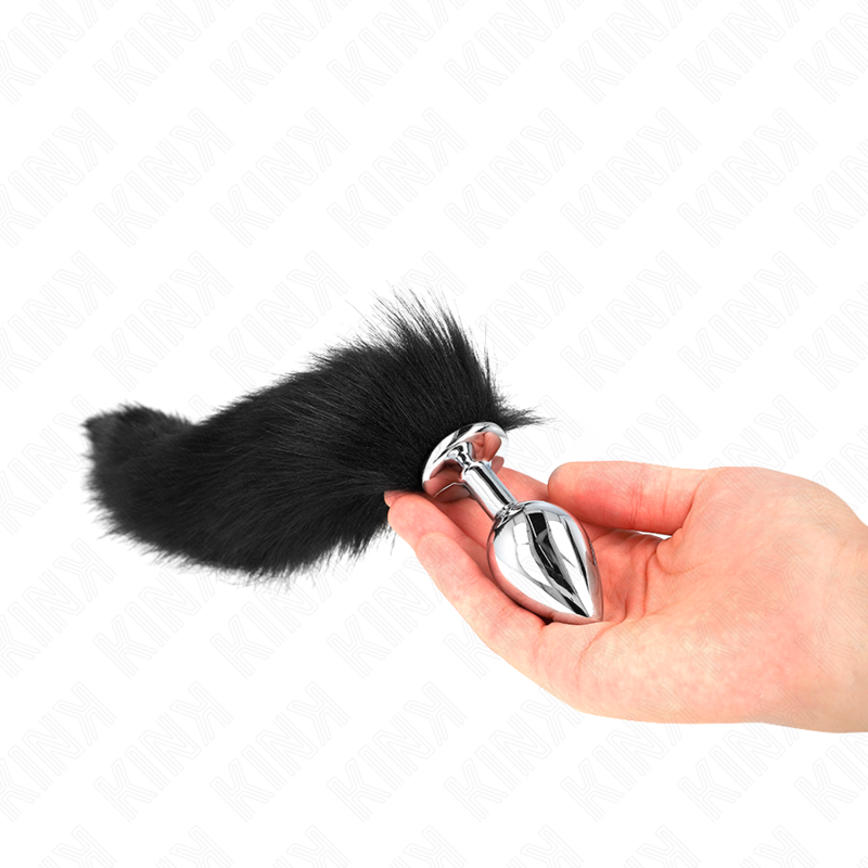 Kink Pleasure Plugs plug anal negro con cola sintética, sujetado en la mano.