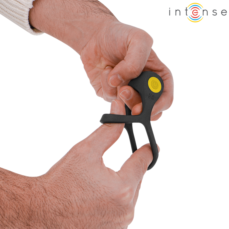 Anillo vibrador negro INTENSE FOR HIM sostenido con las manos, con botón amarillo visible.