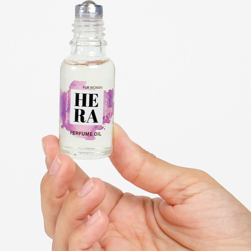 Detalle del roll-on HERA de Secretplay Cosmetic en frasco de vidrio, sujeto con la mano y con la etiqueta frontal visible.