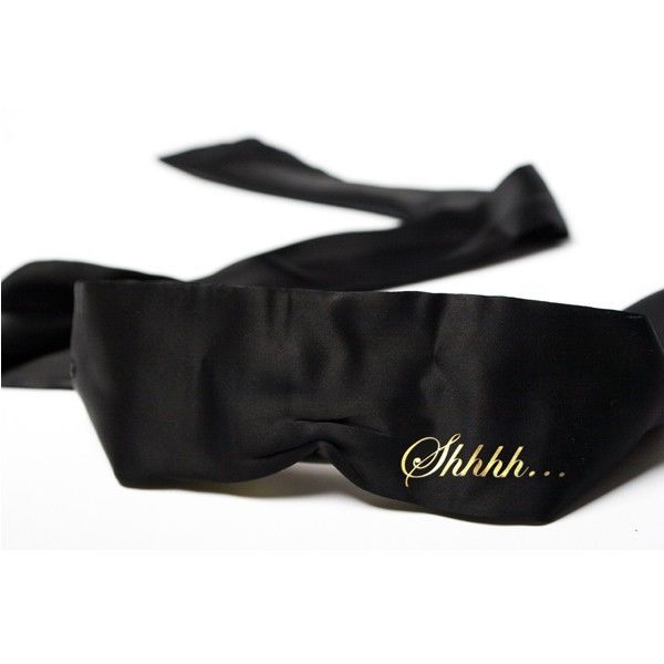 Antifaz negro Bijoux Indiscrets Shhh con cinta de satén y texto dorado.